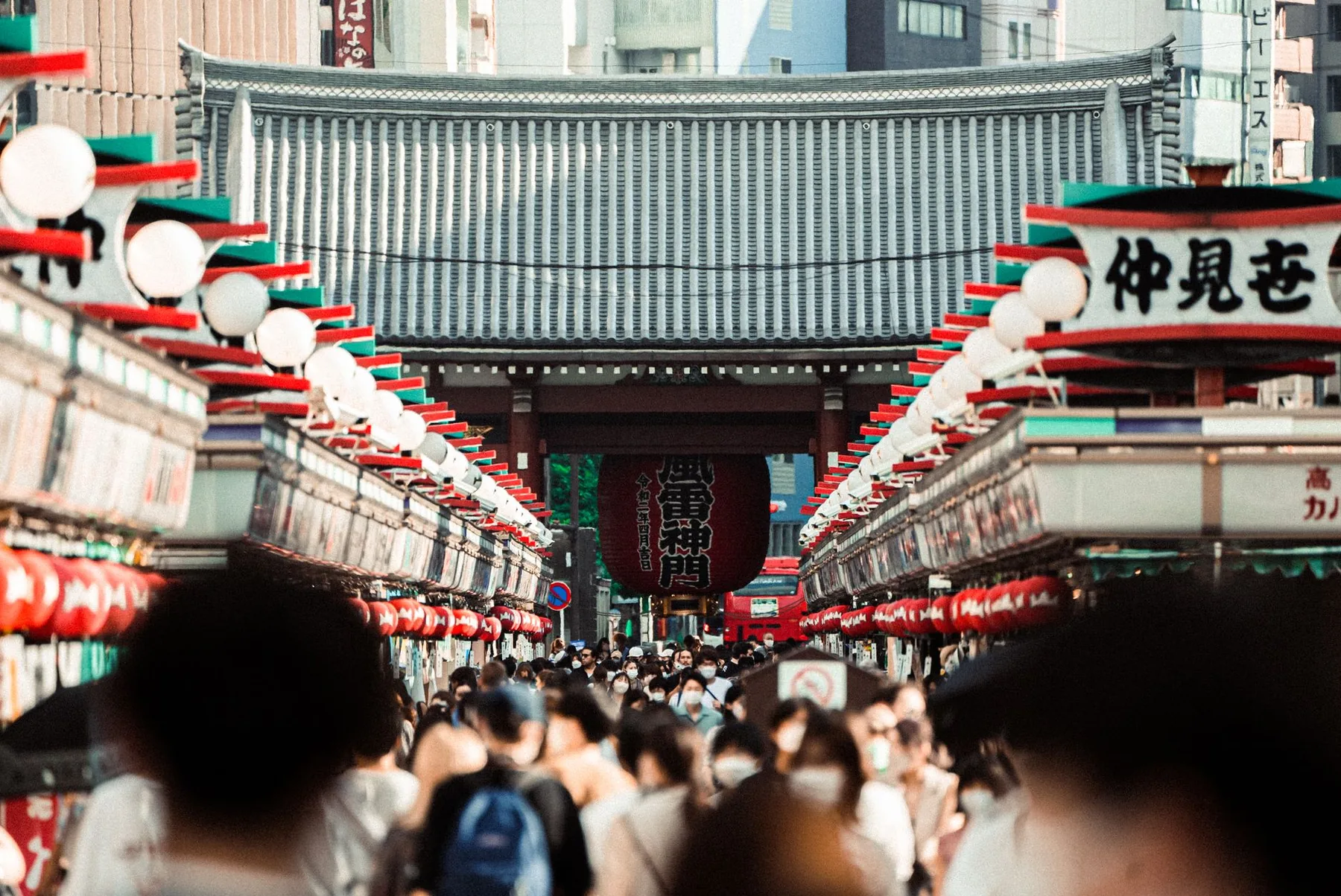 Nakamise street in Asakusa, Tokyo, lined with paper lanterns and shopfronts and leading to a temple gate